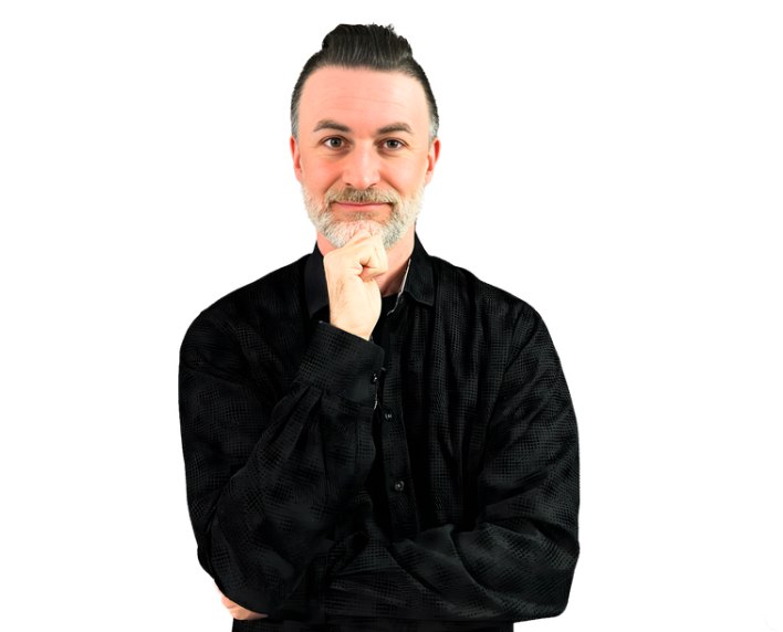 Gary Palmer Jr., Founder and CEO of TechnoRealism, wearing a black shirt with arms crossed in a thoughtful pose